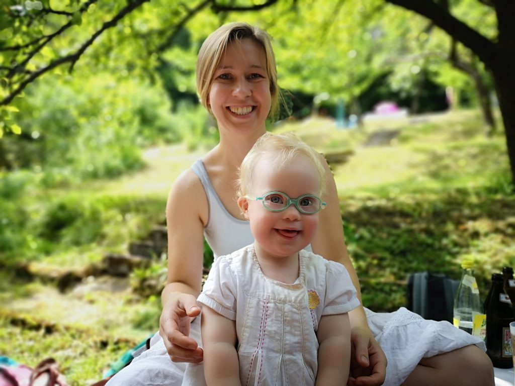 Kleinkind mit Down Syndrom mit Mama im Grünen