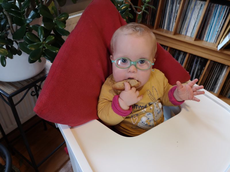 Baby mit Down Syndrom isst Brot