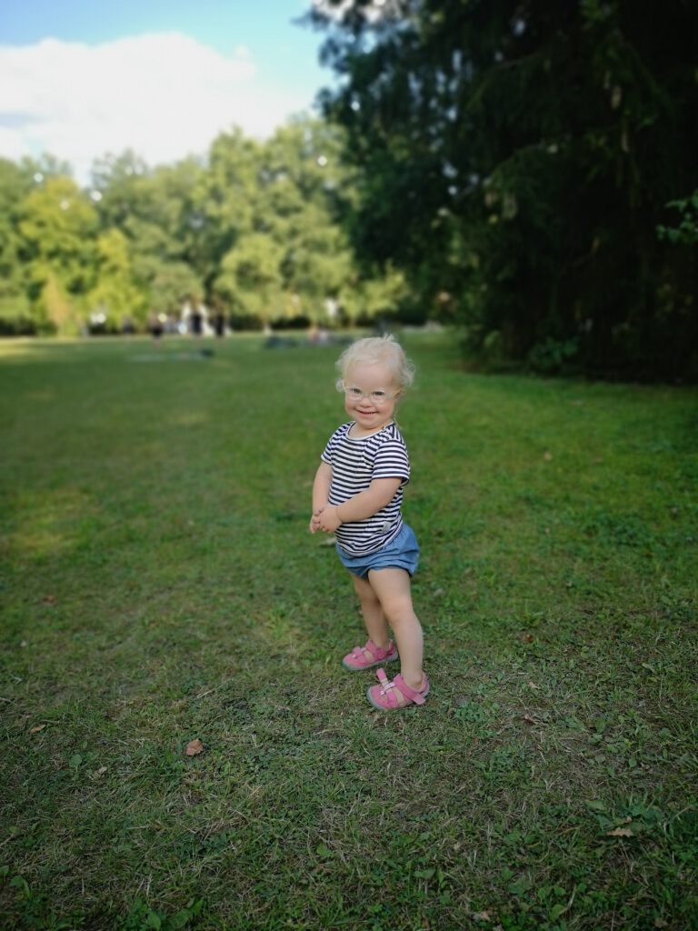 Kleines Mädchen mit Down Syndrom steht im Park